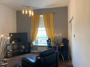 a living room with a chair and a table with a television at Ayr Apartment with Sea and Countryside views in Ayr