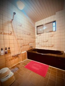 a bathroom with a bath tub and a red rug at Hotel Sagano (Adult only) in Kyoto