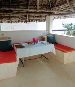 a room with a table and two benches and a table and chairs at Furaha House in Shela