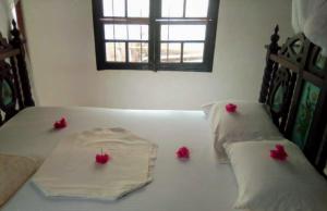 a bed with two pillows with red flowers on it at Furaha House in Shela