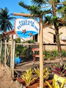 ein Schild für ein Resort mit einer Palme und einem Zaun in der Unterkunft Pousada Estrela do Mar in Barra Grande