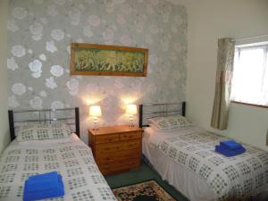 1 dormitorio con 2 camas y ventana en Cae Berllan Cottages en Groeslon