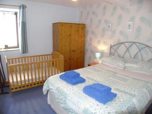 a bedroom with a bed with two blue towels on it at Cae Berllan Cottages in Groeslon