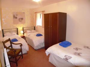 1 dormitorio con 2 camas, armario y silla en Cae Berllan Cottages en Groeslon