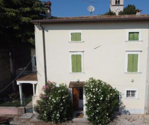 a white house with two bushes in front of it at Casale storico Enzo in Castelnuovo del Garda