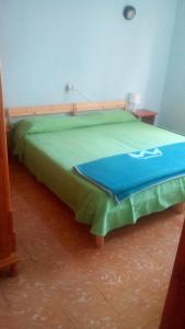 a bed with a green blanket on top of it at Las Gaviotas in Punta del Hidalgo