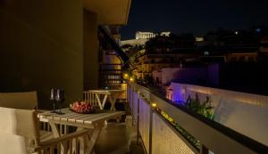 einen Balkon mit einem Tisch und Blick auf die Stadt in der Nacht in der Unterkunft Acropolis Grand Apartment in Athen