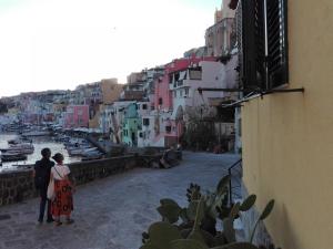 a couple walking down a street looking at a harbor at RESIDENZA MENA marina CORRICELLA in Procida