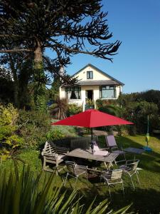 a table and chairs with a red umbrella in front of a house at Norwegian Wood in Paignton