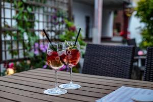two glasses of wine sitting on a wooden table at Hotel & Restaurant Arnoldusklause in Düren - Eifel