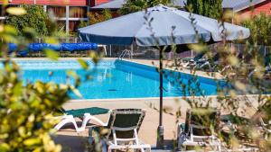 a swimming pool with chairs and an umbrella at Vacanceole - Relais du Plessis in Chaveignes