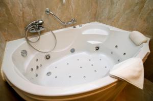 a white bath tub in a bathroom at Hotel Ködmön in Eger