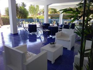 una hall con sedie e tavoli bianchi e un patio di Nido Colorato B&B a Fontane Bianche