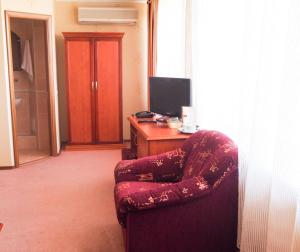 a room with a chair and a desk with a computer at AMAKS Azov Hotel in Azov