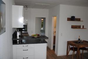 a kitchen with white cabinets and a wooden table at Ferienwohnung Wackerballig in Gelting