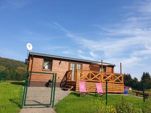 a tiny house with pink chairs in the yard at Modraszkowe Domki in Radków