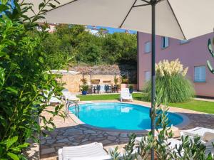 a pool with chairs and an umbrella in a yard at Apartment Chantal-3 by Interhome in Rabac
