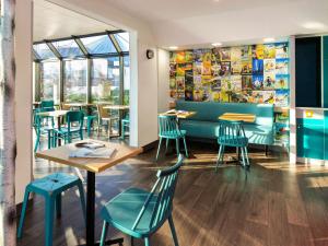 un restaurante con sillas azules, mesas y ventanas en hotelF1 Nancy Sud, en Houdemont