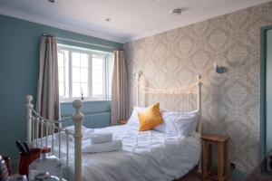a bedroom with a bed with white sheets and yellow pillows at Clovelly Guest House in Lyme Regis