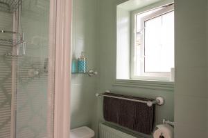 een badkamer met een douche, een toilet en een raam bij Clovelly Guest House in Lyme Regis