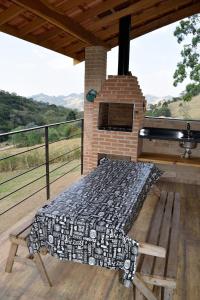 a bed on a deck with a brick fireplace at Chalés Boa Vista in Gonçalves