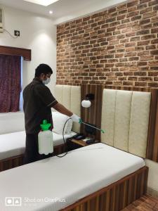 ムンバイにあるHotel Mogul Palace - Near CST Stationの男が部屋のベッドを洗っている