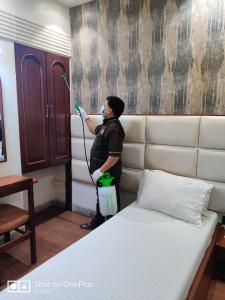 Um homem está a pintar um quarto com uma cama. em Hotel Mogul Palace - Near CST Station em Mumbai