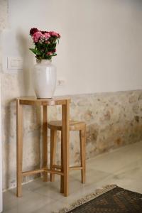un vase avec des fleurs sur une table avec un tabouret dans l'établissement Rimondi Residences Rethymno, à Réthymnon
