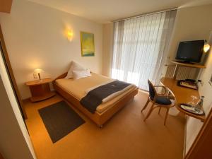 a bedroom with a bed and a desk and a television at Taranga Tagungszentrum und Hotel in Waffensen