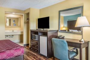 a hotel room with a bed and a desk with a television at Econo Lodge Hotel Bradford in Bradford