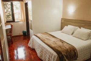 a bedroom with a bed and a window and a desk at Colinas Executive Park Hotel in Giruá