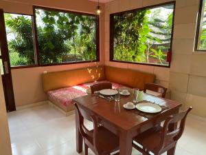 uma sala de jantar com uma mesa e duas janelas em Villa Anjing 2 em Nusa Dua