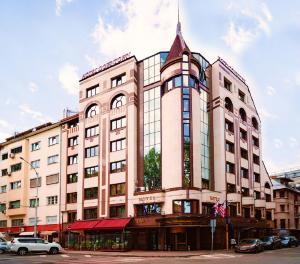 Hotel Downtown - TOP location in the heart of Sofia city في صوفيا: مبنى وردي كبير مع سيارات متوقفة أمامه
