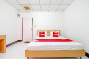 a bedroom with a bed with two red pillows at OYO 525 MRT Phetkasem 48-1 Place in Bangkok