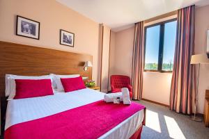 um quarto de hotel com uma cama grande e uma cadeira vermelha em Hospedium Hotel Casino Del Tormes em Salamanca