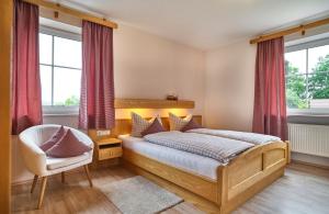 Schlafzimmer mit einem Bett, einem Stuhl und Fenstern in der Unterkunft Haus Wiesengrund in Frauenau
