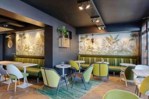 un restaurante con mesas y sillas y una pintura de palmeras en Kyriad Crepy En Valois en Crépy-en-Valois