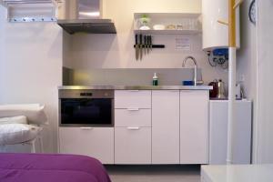 uma cozinha com armários brancos e um lavatório em Chueca - Room Apartments em Madri