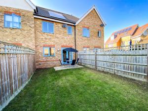 a brick house with a fence and a yard at Contractor Accommodation Specialist, 3 bedroom house with FREE Parking, Wifi & Netflix! in Milton Keynes
