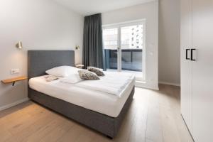 - une chambre avec un grand lit et une fenêtre dans l'établissement Brera Serviced Apartments Leipzig, à Leipzig