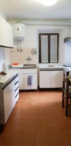 a large kitchen with white cabinets and a tile floor at Appartamento Piccolo Porto di Cerro in Laveno-Mombello