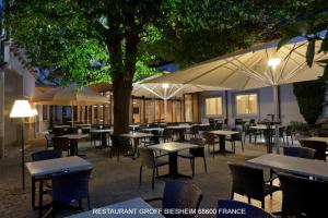 a group of tables and chairs under a tree at Aux Deux Clefs - Hôtel Restaurant Groff in Biesheim