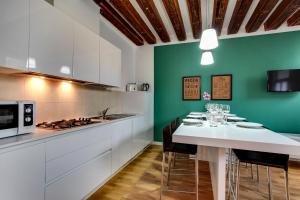 a kitchen with white cabinets and a green wall at Cannaregio suite with garden in Venice
