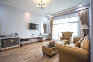 a living room with a couch and chairs and a tv at Eireann Boutique Hotel in Prakhon Chai