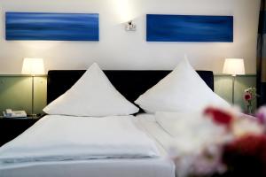 two beds with white pillows in a hotel room at Hotel im Kupferkessel in Cologne