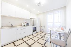 a kitchen with white cabinets and a table and chairs at 1к апартаменты в мкр Европейский АКВАПАРК in Tyumen