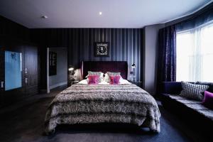 a bedroom with a large bed with pink pillows at Malmaison Dundee in Dundee