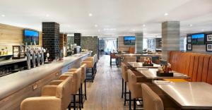 a restaurant with a long bar with chairs and tables at The Belfry Hotel & Resort in Sutton Coldfield