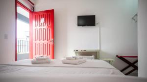 1 dormitorio con cama blanca y puerta roja en Urbano Suítes, en Ubatuba