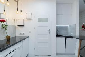 Una cocina blanca con gabinetes blancos y un fregadero. en Crystal Apartment Katowice III, en Katowice